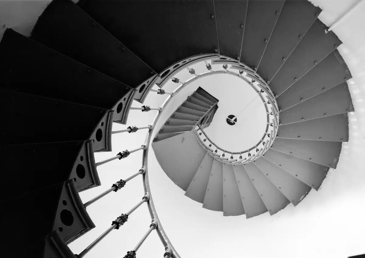 Looking up a cast-iron spiral stair toward the lantern, from an archival building survey